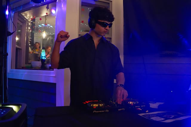 DJ Frieds throwing a fist in the air behind the decks in blue light