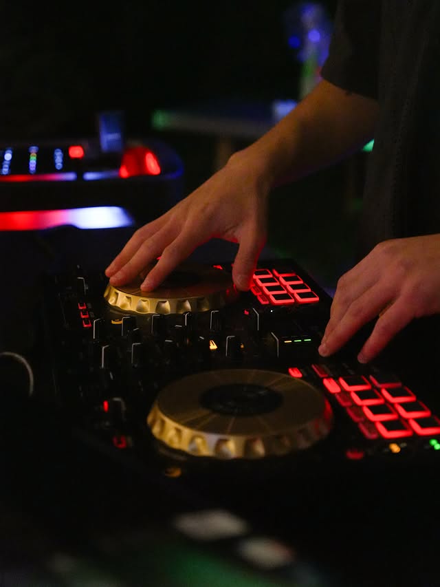 Close-up of hands on the Pioneer DJ controller with red pads lit
